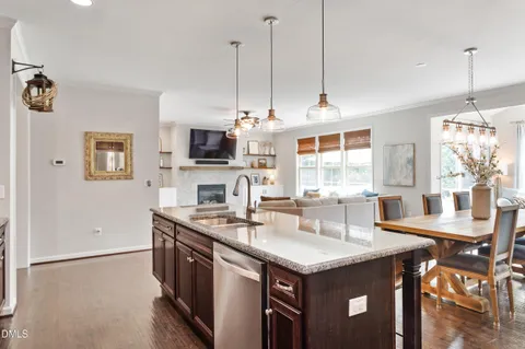 a kitchen with stainless steel appliances granite countertop a sink a stove and a wooden floor