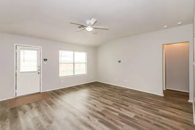 a view of an empty room with wooden floor and a window