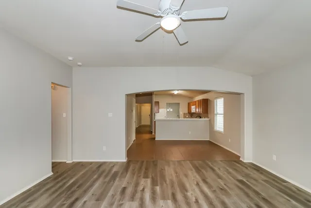 a view of empty room with wooden floor and fan