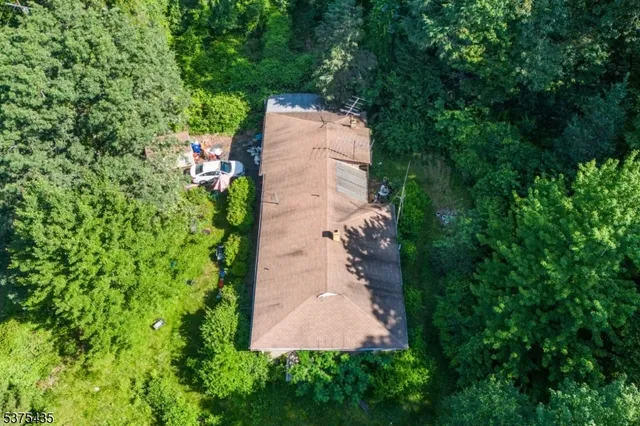 an aerial view of a house with a yard and trees all around