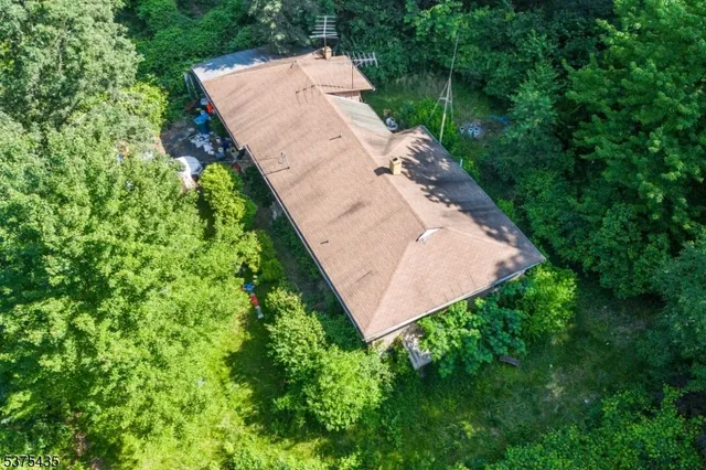 an aerial view of a house with a yard and trees all around
