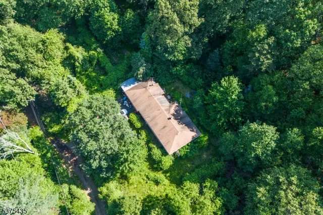 an aerial view of residential house with outdoor space and trees all around