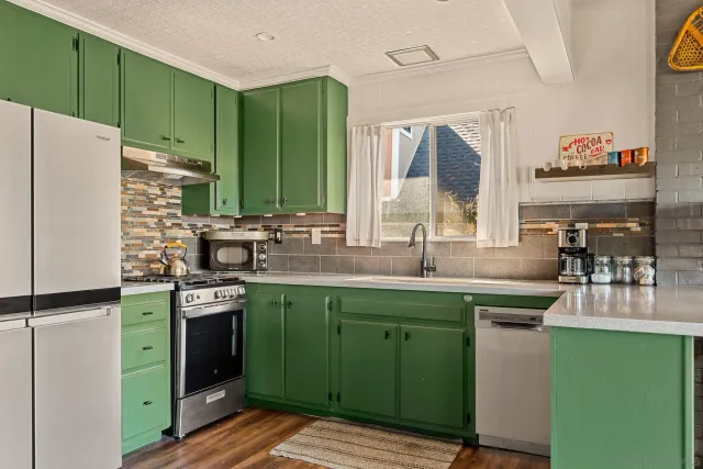 a kitchen with stainless steel appliances granite countertop a refrigerator a sink dishwasher a stove and a refrigerator