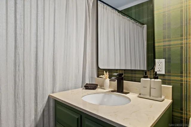 a bathroom with a granite countertop sink and a mirror