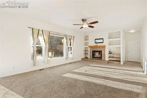 an empty room with windows and ceiling fan