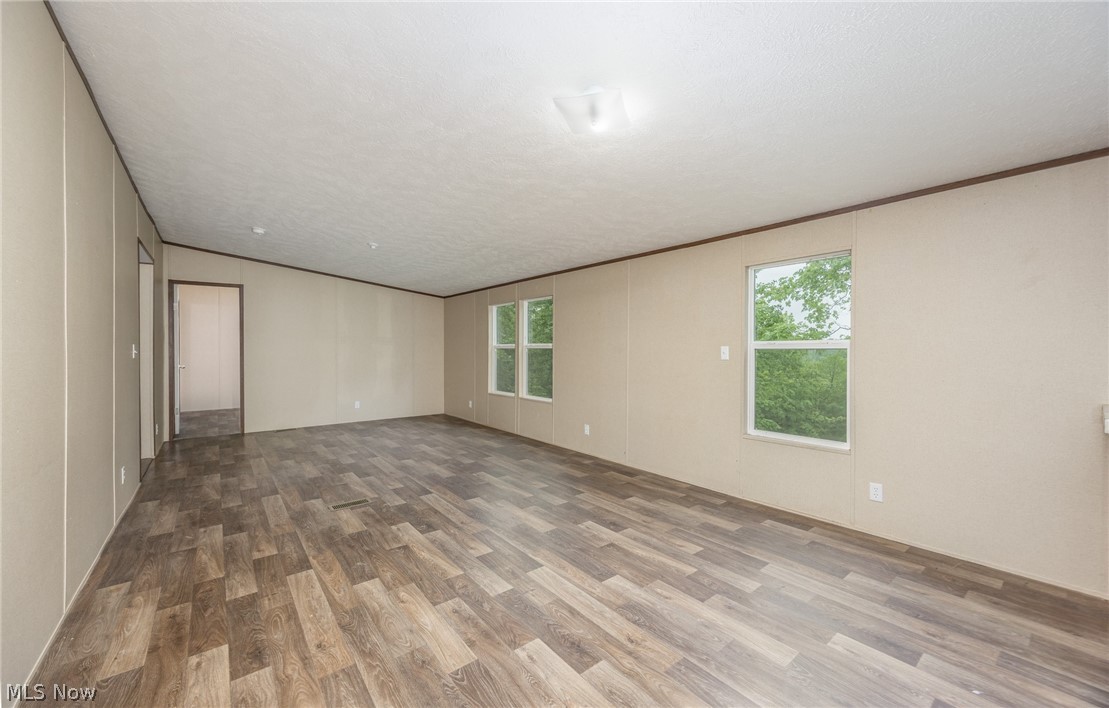 7455 Stanleyville Road Whipple, OH 45788 - Photo 13 of 37 Spacious interior featuring wood-finish flooring, light neutral wall panels, white trim, and multiple windows