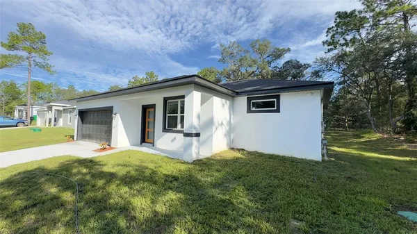a front view of house with yard and trees in the background