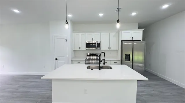 a kitchen with kitchen island a sink stainless steel appliances and refrigerator