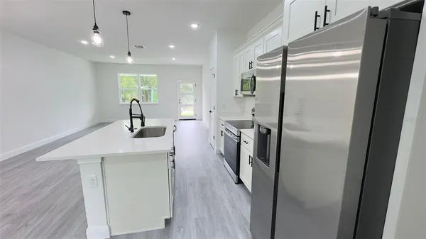 a kitchen with stainless steel appliances a refrigerator a sink and a stove top oven