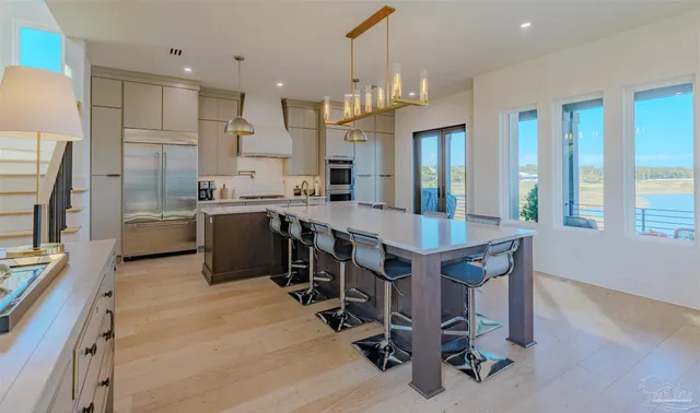 a kitchen with stainless steel appliances a sink a stove a refrigerator cabinets and a dining table