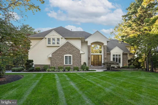 a front view of a house with a garden and trees