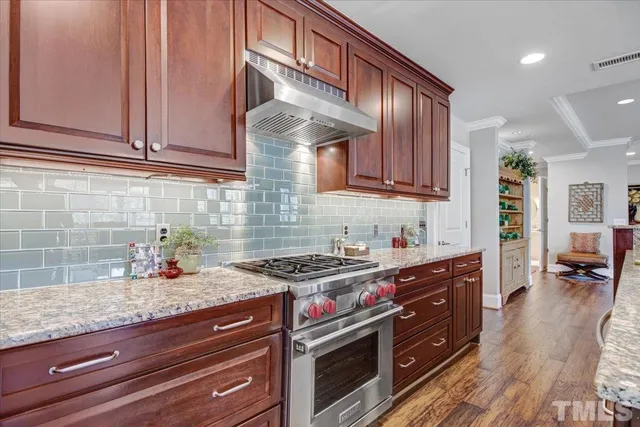 a kitchen with stainless steel appliances granite countertop a stove a sink and dishwasher wooden cabinets with granite countertops