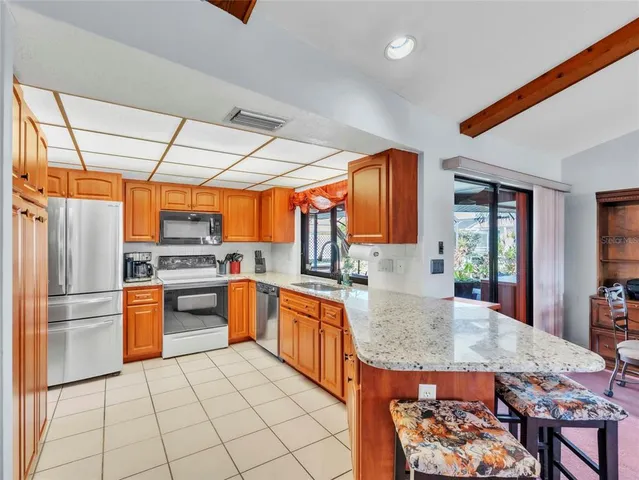 a kitchen with stainless steel appliances granite countertop a refrigerator a stove top oven and a sink
