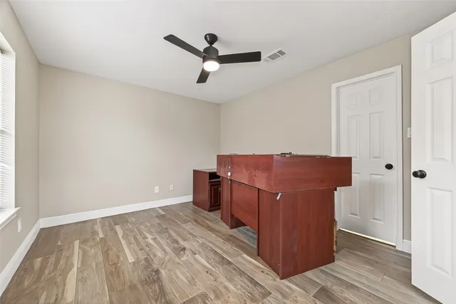 an empty room with wooden floor cabinet and windows