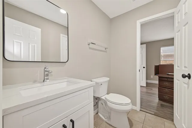 a bathroom with a toilet a sink a mirror and vanity