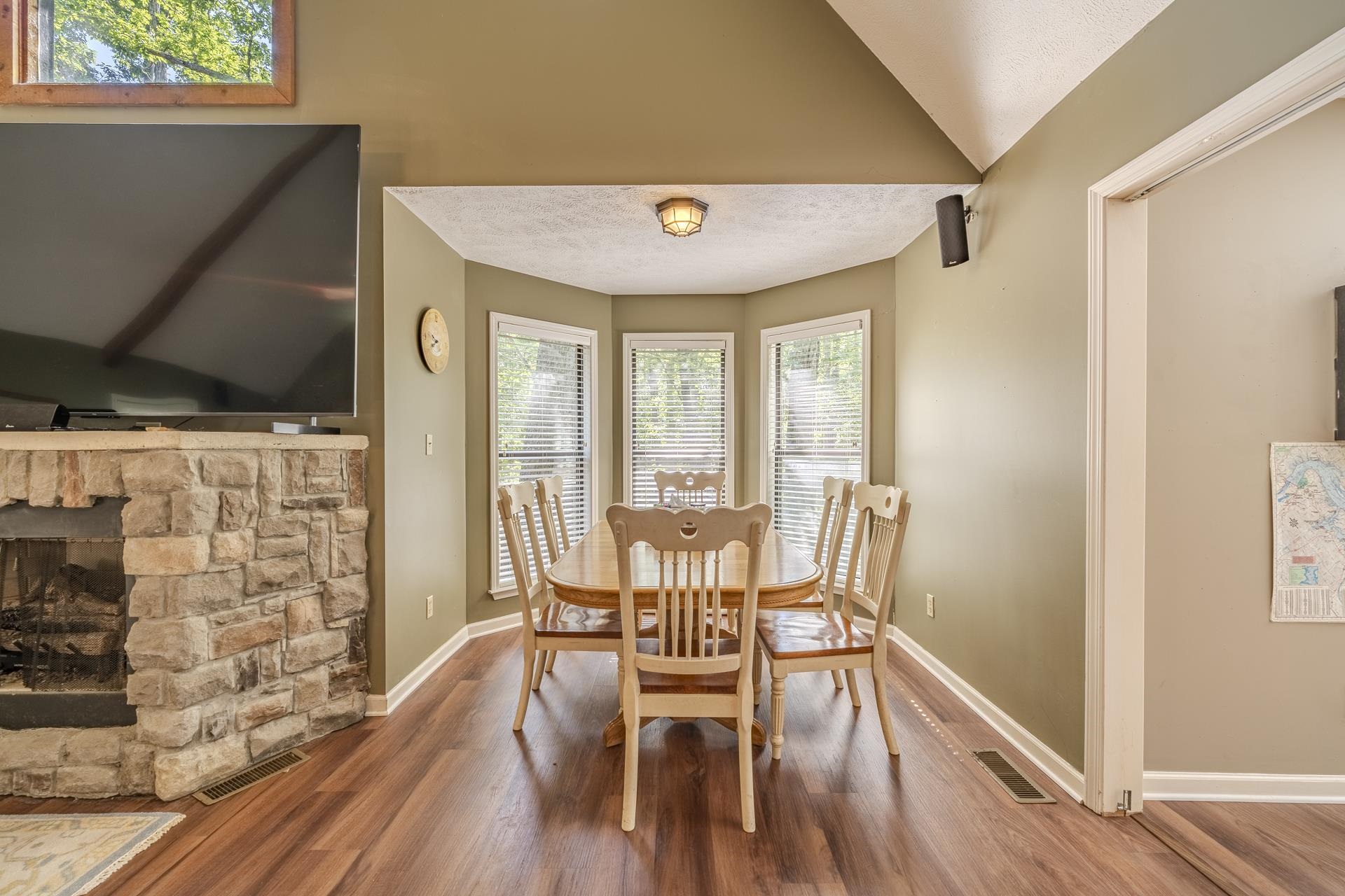 435 Murray Lane Counce, TN 38326 - Photo 10 of 34 Dining area featuring a bay window with multiple panes, wood-finish flooring, and a stone-faced fireplace