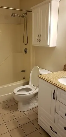 a bathroom with a granite countertop toilet a sink and a shower