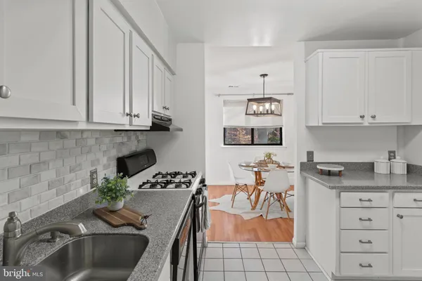 a kitchen with granite countertop a sink a stove and cabinets
