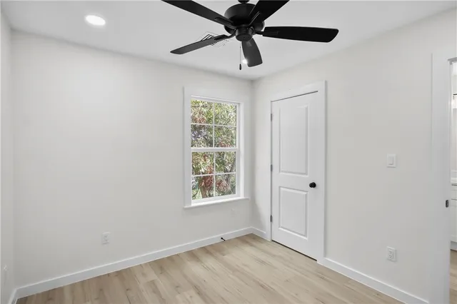 an empty room with windows and ceiling fan