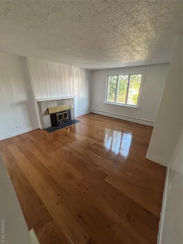 a view of an empty room with window and fireplace