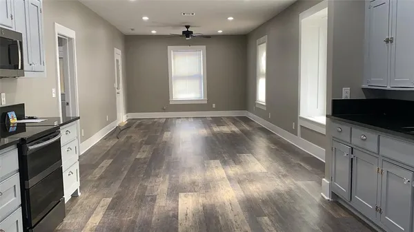 a view of empty room with wooden floor and fan