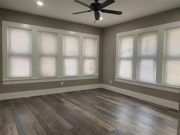 a view of an empty room with a window and wooden floor