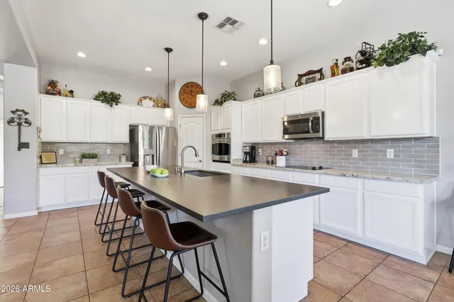 a kitchen with stainless steel appliances kitchen island granite countertop a sink a stove and a counter top space