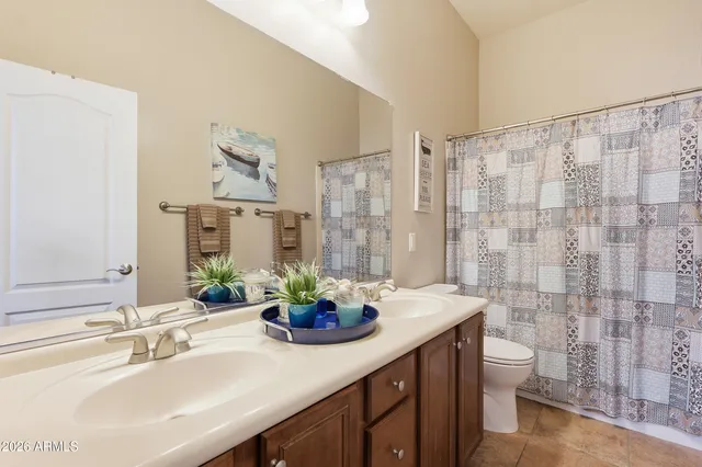 a bathroom with a granite countertop sink a toilet a mirror and shower curtain