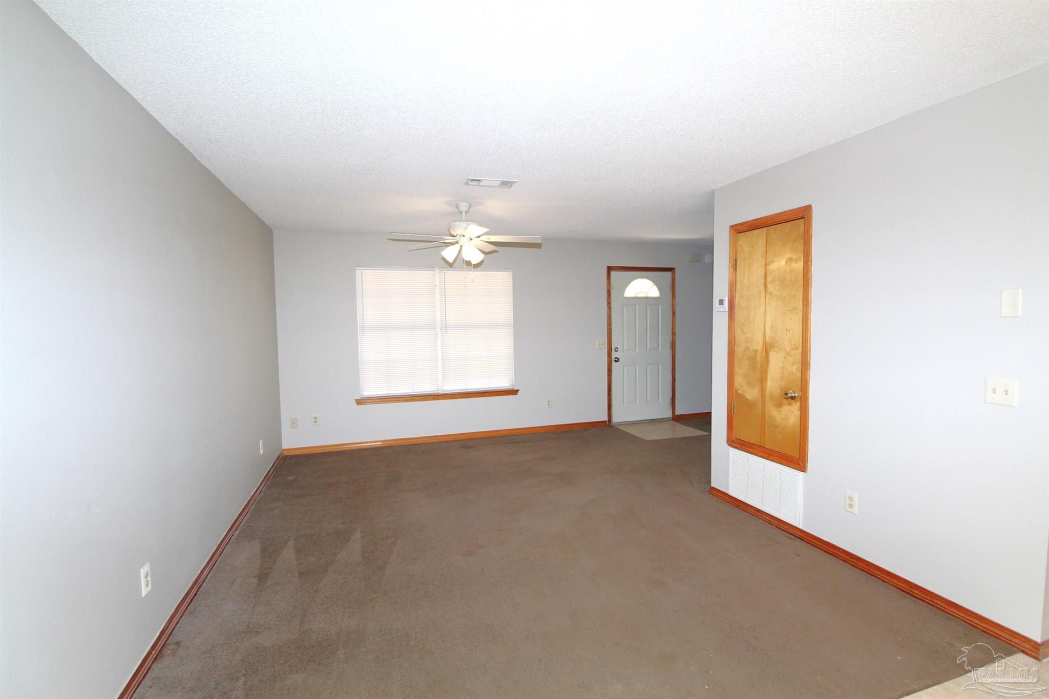 5306 Windham Road Milton, FL 32570 - Photo 2 of 15 an empty room with windows and chandelier fan