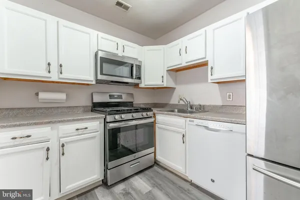 a kitchen with granite countertop white cabinets and white appliances