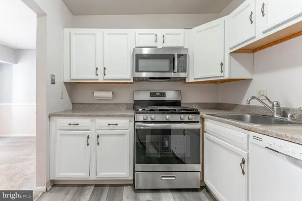a kitchen with white cabinets stainless steel appliances and sink