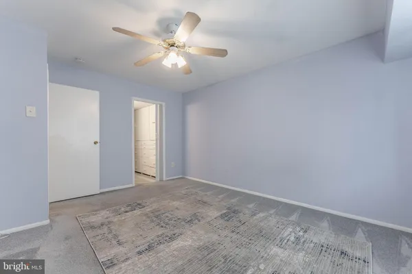 an empty room with chandelier fan and windows