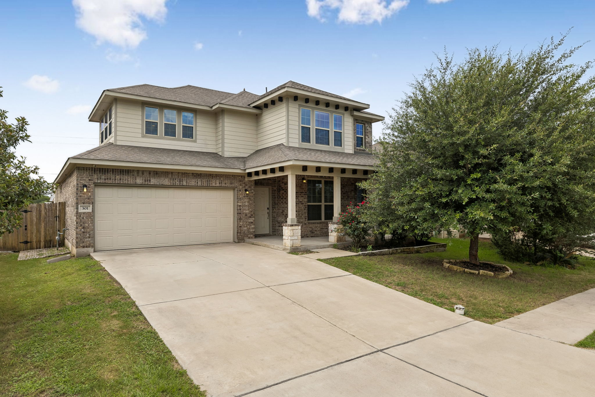A classic brick and siding home, featuring an attached garage and welcoming covered front porch, ready for new occupants.