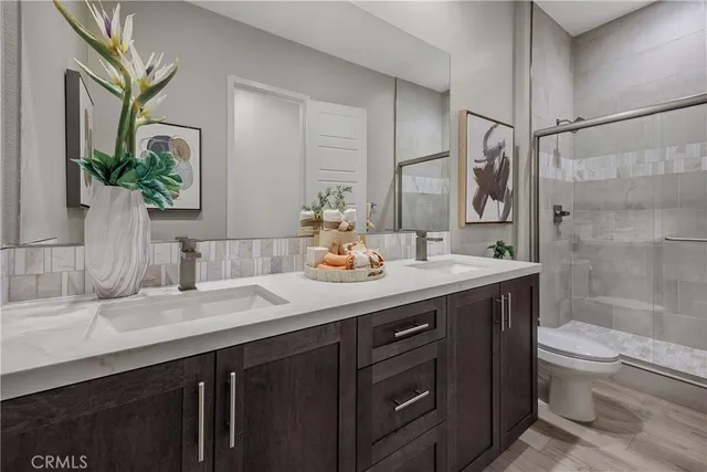 a bathroom with a granite countertop sink a toilet a mirror and shower