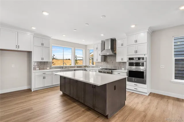 a large kitchen with cabinets wooden floor and stainless steel appliances