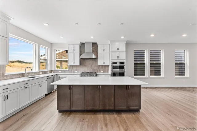 a large kitchen with stainless steel appliances granite countertop a stove a sink dishwasher a microwave oven and a large countertops with wooden floor