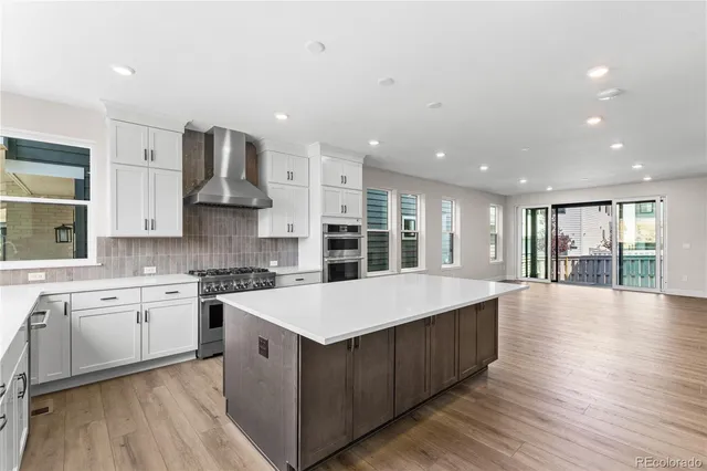 a large kitchen with stainless steel appliances kitchen island a large counter top and a wooden floors
