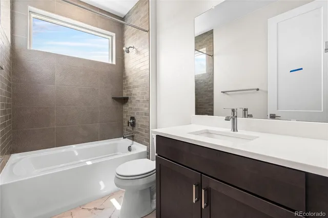 a bathroom with a bathtub shower sink vanity mirror and toilet