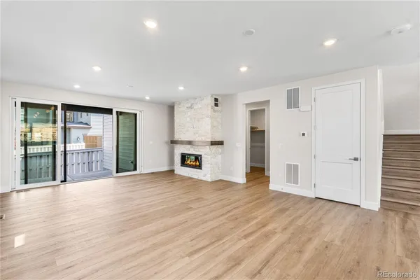 a view of an empty room with wooden floor and windows