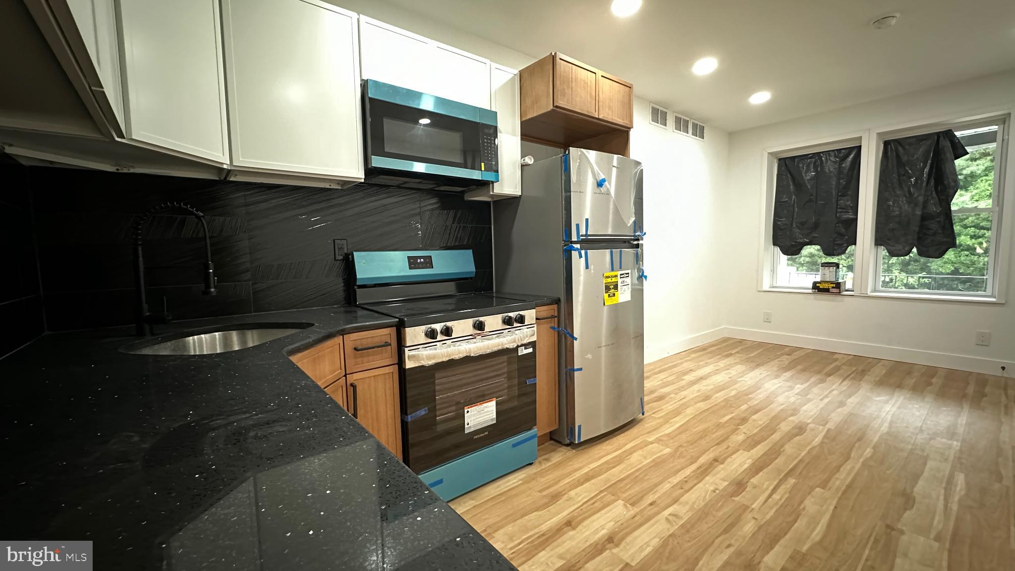 3924 North 13th Street, Unit A Philadelphia, PA 19140 - Photo 16 of 18 a kitchen with stainless steel appliances granite countertop a stove a refrigerator and a microwave