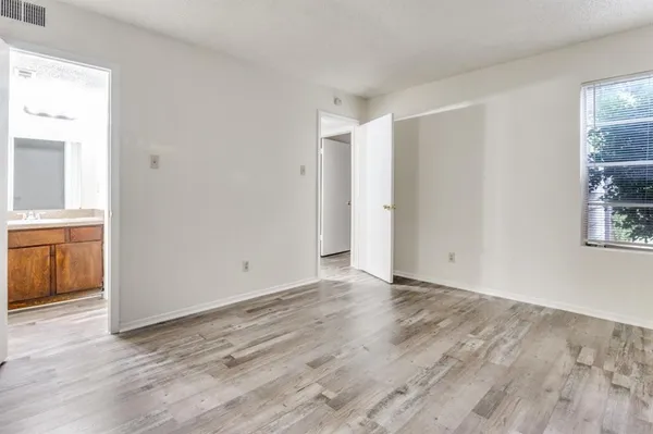 a view of an empty room with window and wooden floor