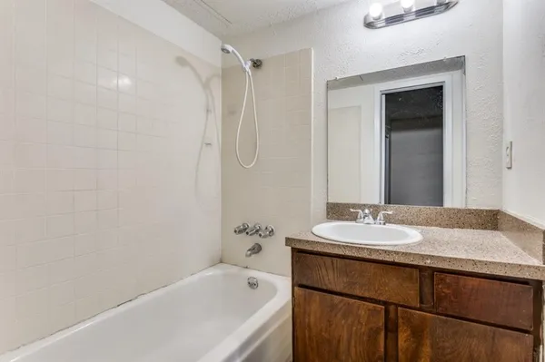 a bathroom with a granite countertop sink mirror and a bath tub