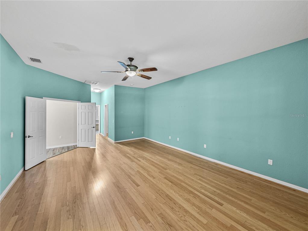 4004 Sable Loop Drive Lake Wales, FL 33859 - Photo 23 of 94 an empty room with wooden floor and chandelier fan