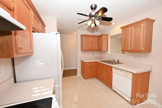 a kitchen with stainless steel appliances granite countertop a sink a stove a refrigerator a washer dryer and white cabinets