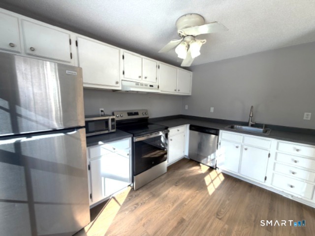 113 Heather Ridge, Unit 113 Shelton, CT 06484 - Photo 7 of 19 a kitchen with cabinets stainless steel appliances and wooden floor