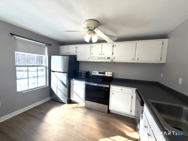 113 Heather Ridge, Unit 113 Shelton, CT 06484 - Photo 8 of 19 a kitchen with granite countertop a stove a sink dishwasher and a microwave oven with white cabinets