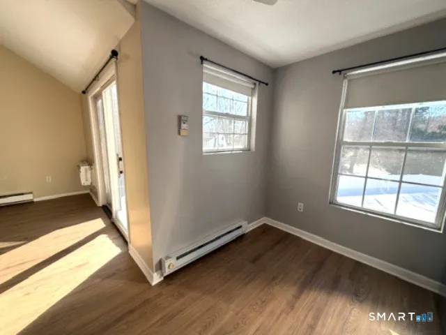 an empty room with wooden floor and windows