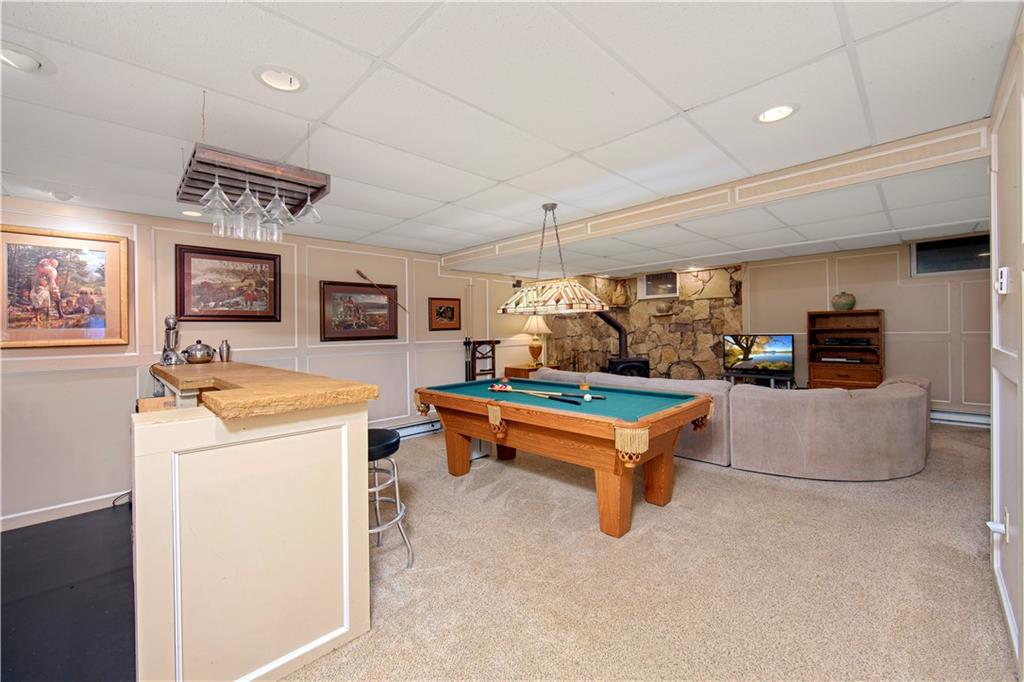 1479 Three Degree Road Mars, PA 16046 - Photo 17 of 24 8' ceilings, recessed lighting, large built-in bar with shelving, mini fridge, etc. Pool table and light included. Large corner stone surround behind wood-burner. Full bath and another room (currently a gym) are to the right. An unfinished utility room is behind the photographer.