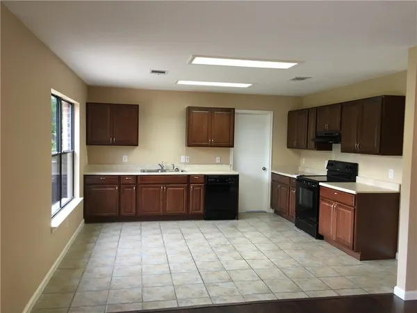 a kitchen with stainless steel appliances granite countertop a stove a sink dishwasher a refrigerator and wooden cabinets