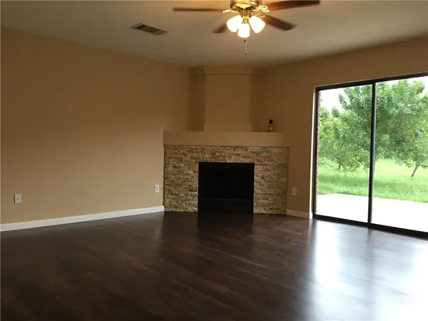 a view of an empty room with wooden floor and a fireplace